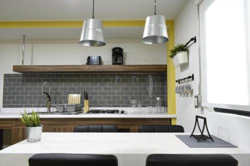 a kitchen with a sink and a counter with chairs at TJ Border Suites by Hosted by Me in Tijuana