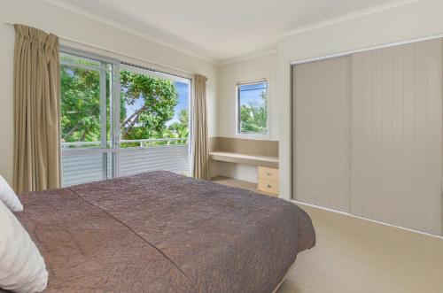 a bedroom with a large bed and two windows at Raumati Sands Resort in Paraparaumu Beach