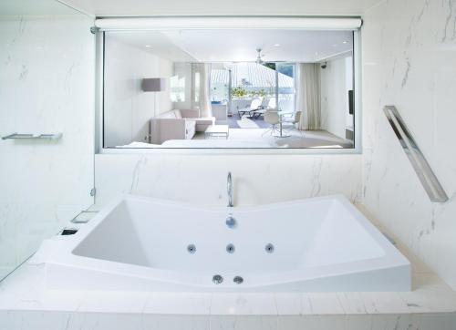 a white bathroom with a large mirror and a tub at Sofitel Noosa Pacific Resort in Noosa Heads