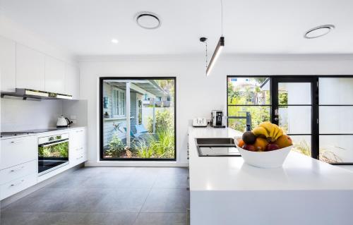 a white kitchen with a bowl of fruit on a counter at Lamour Holiday Beach House in Gold Coast