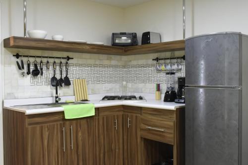 a kitchen with wooden cabinets and a stainless steel refrigerator at TJ Border Suites by Hosted by Me in Tijuana