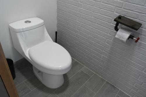 a white toilet in a bathroom with a tile wall at TJ Border Suites by Hosted by Me in Tijuana