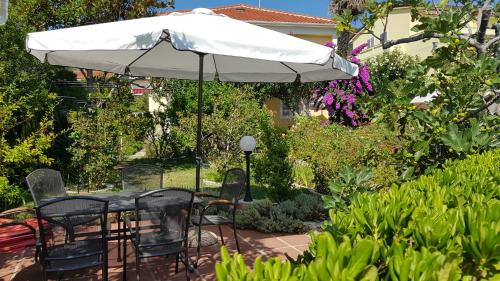 een tafel en stoelen onder een parasol in een tuin bij Apartments Antica in Rab