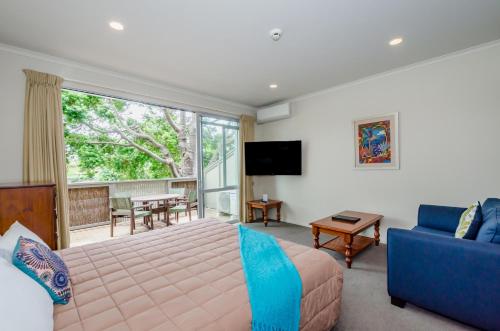a bedroom with a bed and a couch and a tv at Raumati Sands Resort in Paraparaumu Beach