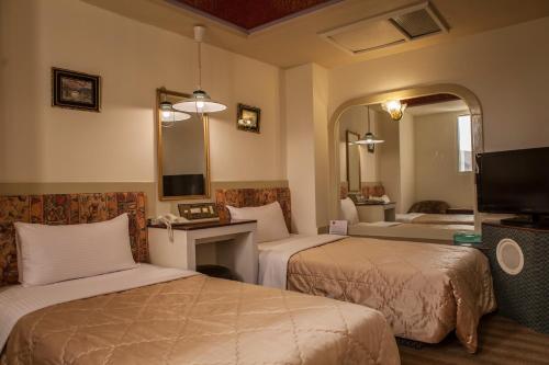 ein Hotelzimmer mit zwei Betten und einem Spiegel in der Unterkunft 真正好旅店 Good Hotel in Fengyuan