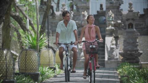 a man and a woman riding bikes down a sidewalk at The Royal Santrian in Nusa Dua