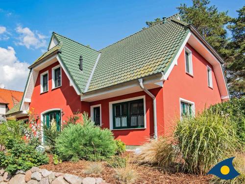a red house with a green roof at Fraeulein Loddin Whg_ Hugo in Kölpinsee