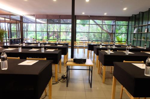 a restaurant with black tables and chairs and windows at Interpark Hotel & Residence, Eastern Seaboard Rayong in Ban Phan Sadet Nok