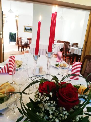 a table with two red candles and flowers on it at Hotel Margit in Trenčianske Teplice