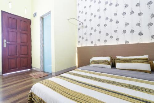 1 dormitorio con 1 cama y puerta de madera en Krisna Hostel, en Medan