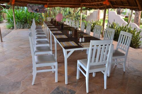 a long table with white chairs and a table at Honey Badger Lodge in Moshi
