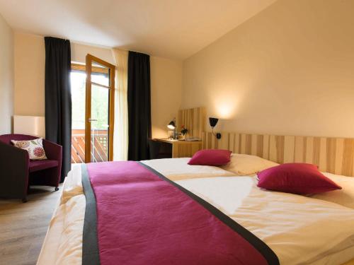 a bedroom with a large bed with red and pink pillows at Brauerei_Gasthof Pfister in Eggolsheim