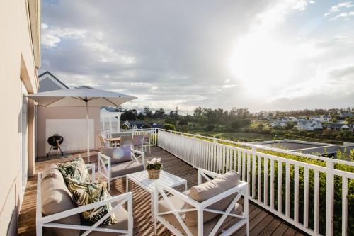 a balcony with chairs and a table and an umbrella at Kingswood Manor No.17 in George