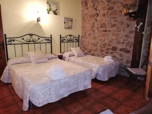 a room with two beds and a stone wall at LA CASUCA Y LA CABAÑA in Ojedo