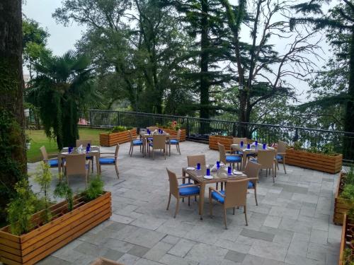 a patio with tables and chairs and trees at Hotel Pine Retreat Mallroad in Mussoorie