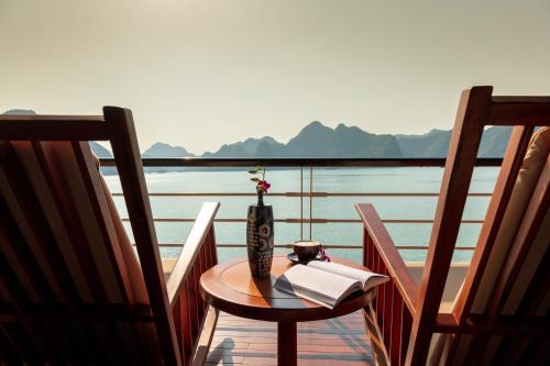 a table with a vase and a book on a balcony at Orchid Premium Cruise in Ha Long