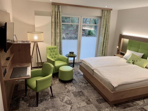 a bedroom with a bed and two green chairs at Landhotel Witte-König in Garrel