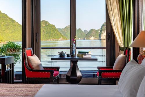 a bedroom with a view of the water and a table and chairs at Orchid Premium Cruise in Ha Long
