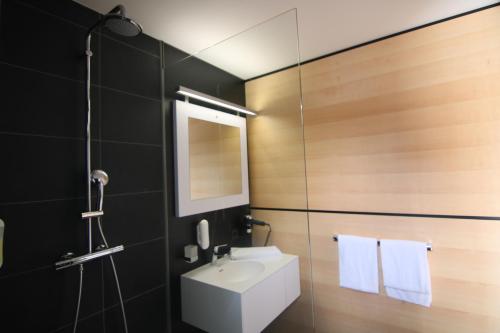 a bathroom with a shower, sink, and mirror at NU Hotel in Neu-Ulm