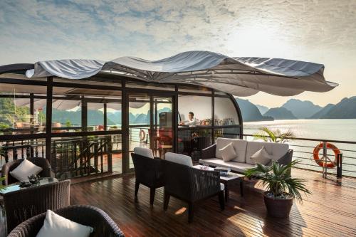 a deck on a boat with a table and chairs at Orchid Premium Cruise in Ha Long