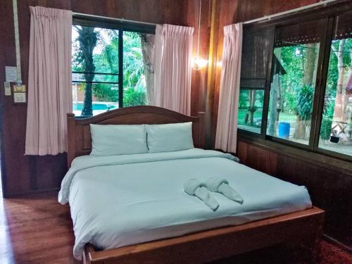 Una cama con dos zapatillas encima. en Pechpailin Resort, en Kanchanaburi