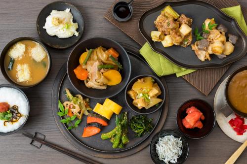 a table with plates of food and bowls of food at Candeo Hotels Nankai Wakayama in Wakayama