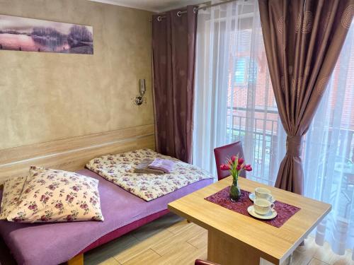 a room with a bed and a table and a window at Klinkierowa Rezydencja Gniezno in Gniezno
