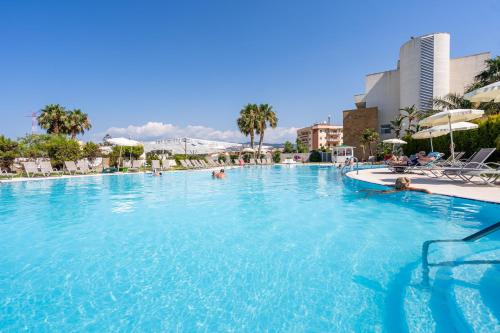a large swimming pool with people in the water at Capo Peloro Hotel in Torre Faro