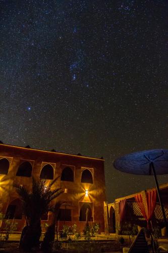 a starry night with a building and a star filled sky at Riad Madu in Merzouga