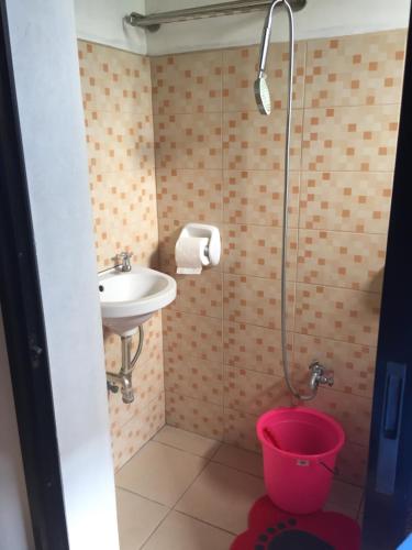 a bathroom with a sink and a shower with a bucket at Ellens Homestay in Irosin