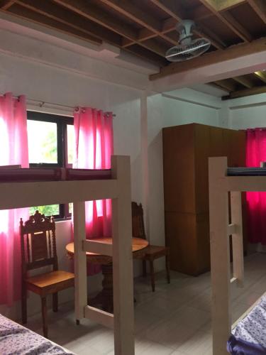 a room with pink curtains and a table and chairs at Ellens Homestay in Irosin