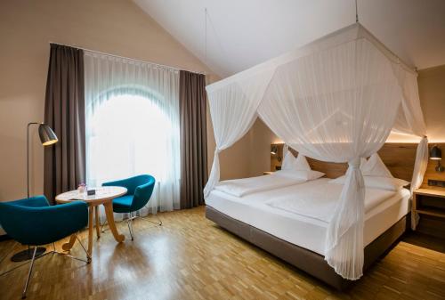 1 dormitorio con cama con dosel, mesa y sillas en Rogner Bad Blumau, en Bad Blumau