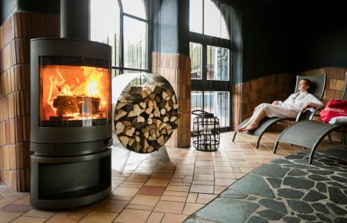 a man sitting in a room with a fireplace at Rogner Bad Blumau in Bad Blumau