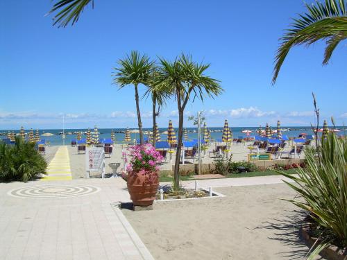 a patio with palm trees and chairs on the beach at Residence Veliero in San Mauro a Mare