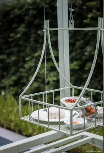 a feeding cage with plates of food in it at Samsen Street Hotel in Bangkok