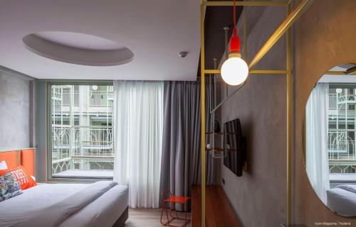 a bedroom with a bed and a large window at Samsen Street Hotel in Bangkok