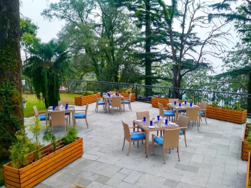 a patio with tables and chairs and trees at Hotel Pine Retreat Mallroad in Mussoorie