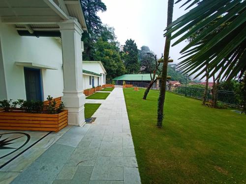 a walkway next to a building with a green yard at Hotel Pine Retreat Mallroad in Mussoorie