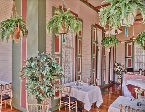 un comedor con mesas, sillas y plantas en Southern Mansion, en Cape May