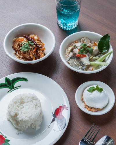 a table with three bowls of food and rice at Samsen Street Hotel in Bangkok