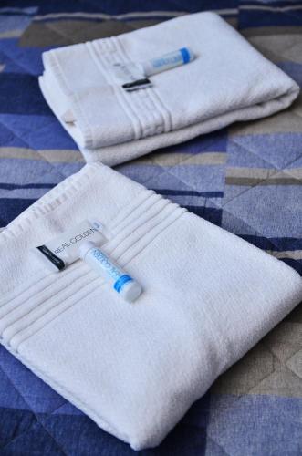 two white towels with a toothbrush on a bed at Pousada Mar Do Leste in Florianópolis