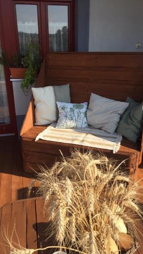 a wooden bench with pillows on a porch at Dósa tanya, Vendégház in Cserépfalu