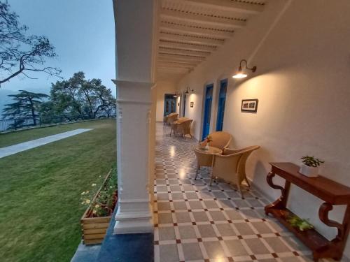 a porch of a house with chairs and a table at Hotel Pine Retreat Mallroad in Mussoorie