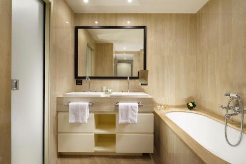 a bathroom with a tub, sink and mirror at Margutta 19 - Small Luxury Hotels of the World in Rome