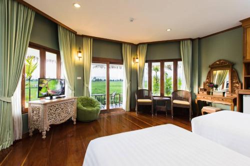 a bedroom with a bed and a television and a desk at Phusanfah Resort in Mae Taeng