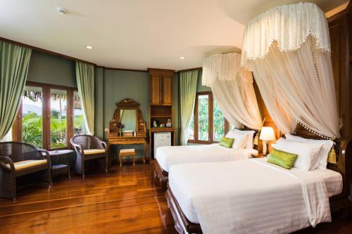 1 dormitorio con 2 camas, escritorio y ventanas en Phusanfah Resort, en Mae Taeng