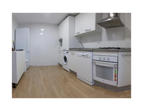 een keuken met witte kasten en een wasmachine en droger bij APTO EDU 3MIN DE LA PLAYA in Fuengirola