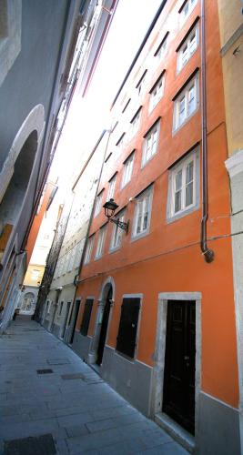 an empty alley with an orange building with windows at Piazza Grande City Residence in Trieste