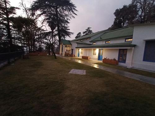 a house with a yard next to a building at Hotel Pine Retreat Mallroad in Mussoorie