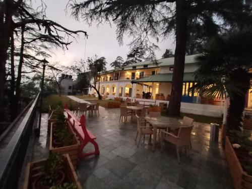 a patio with tables and chairs in front of a building at Hotel Pine Retreat Mallroad in Mussoorie